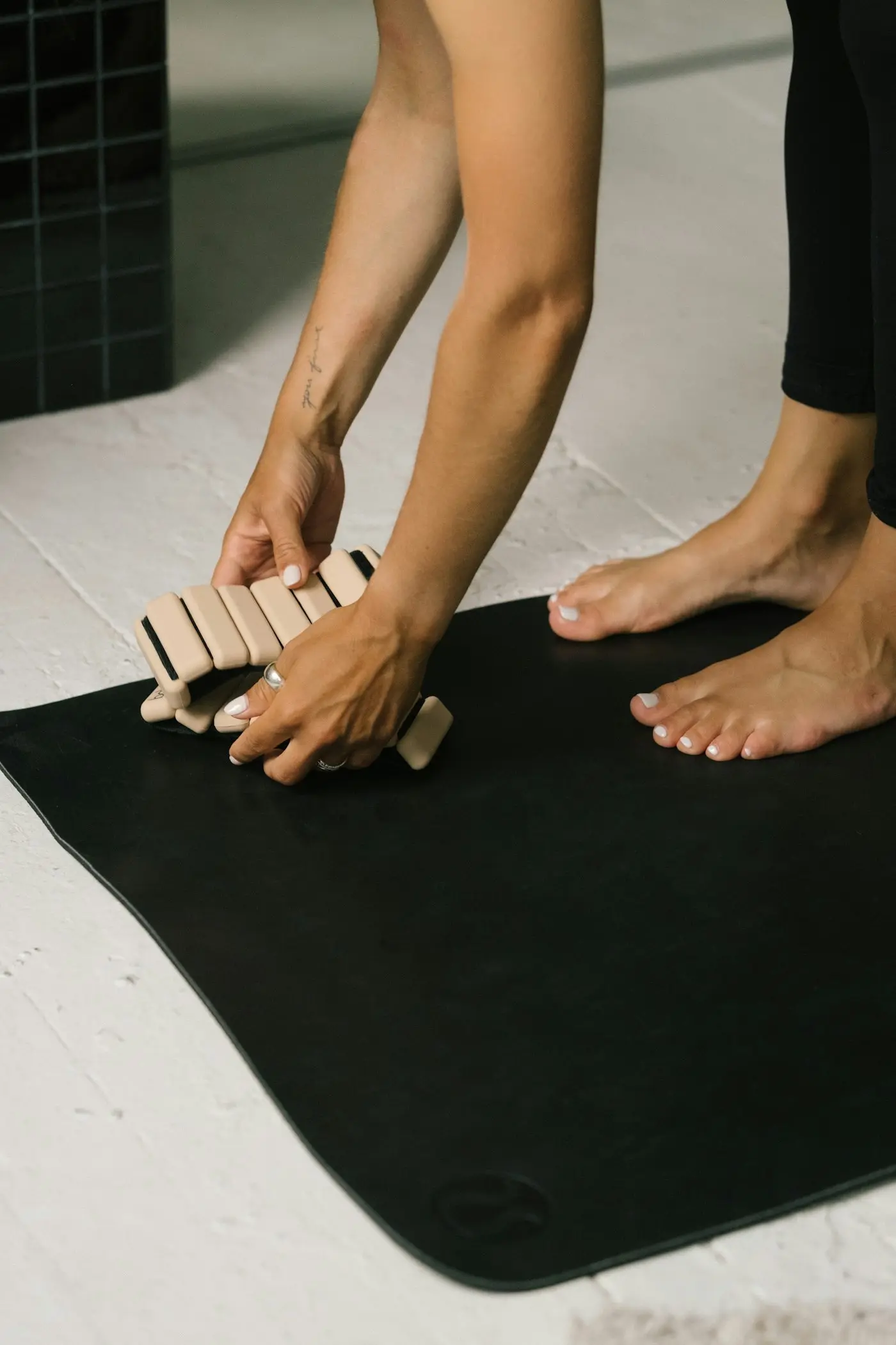 Çıplak ayakların yanında koyu bir mata küçük ahşap bir Pilates aparatı yerleştiren eller